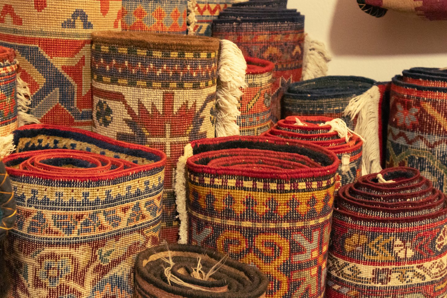 Rolled up patterned carpets with fringed edges in a shop.
