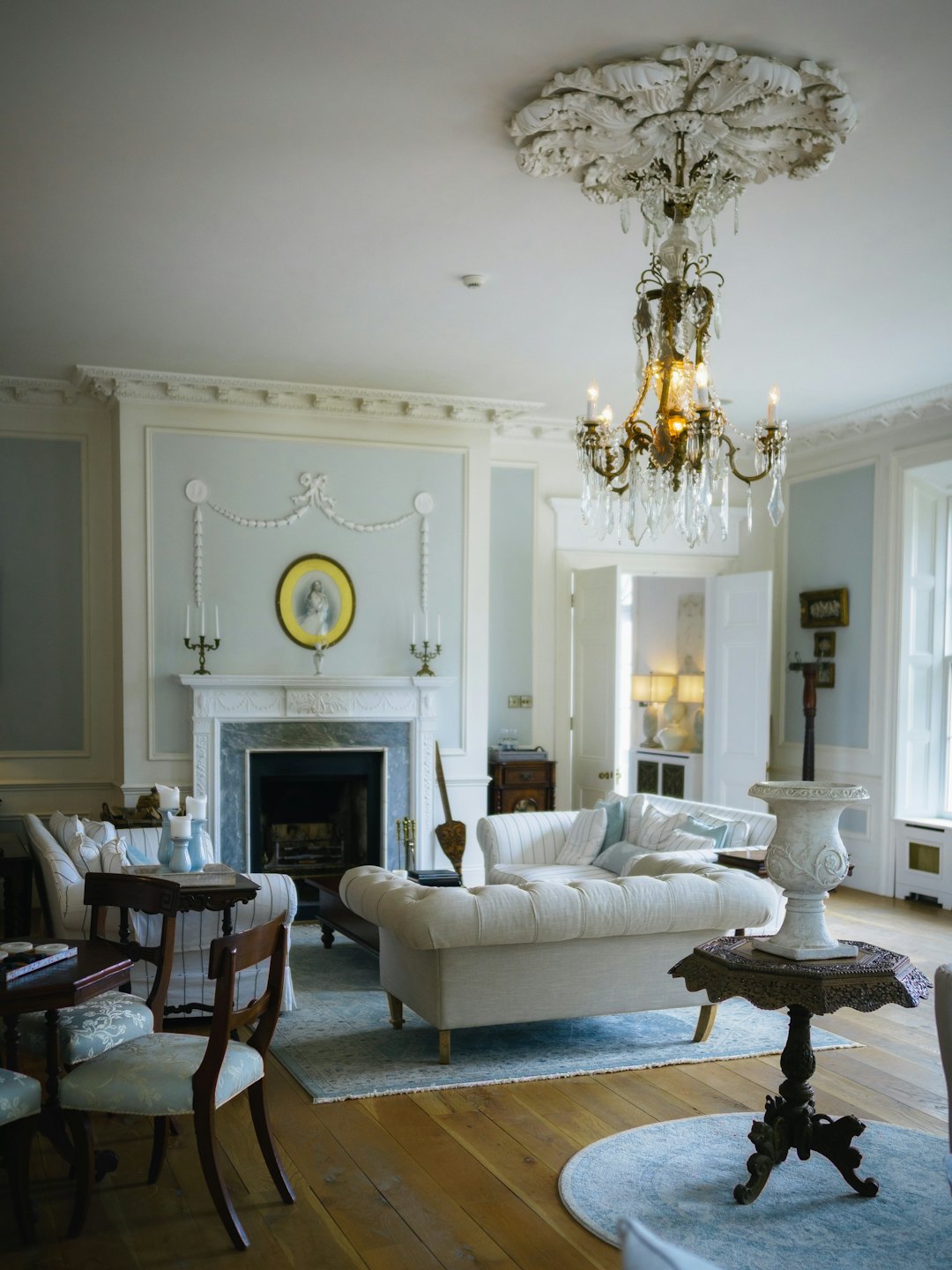 Elegant living room with white sofas and a grand fireplace.