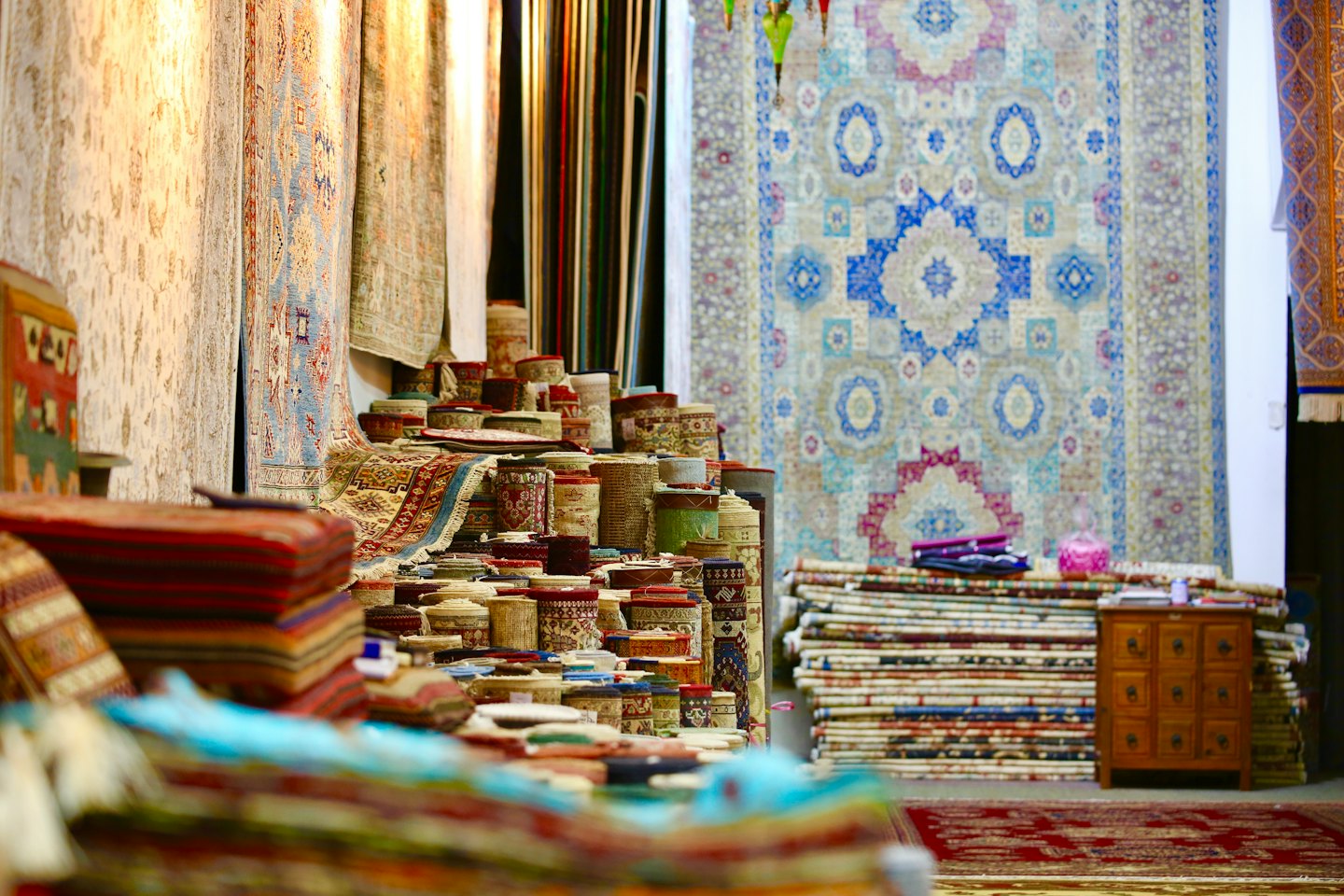Colorful stacked and rolled patterned rugs in a shop.
